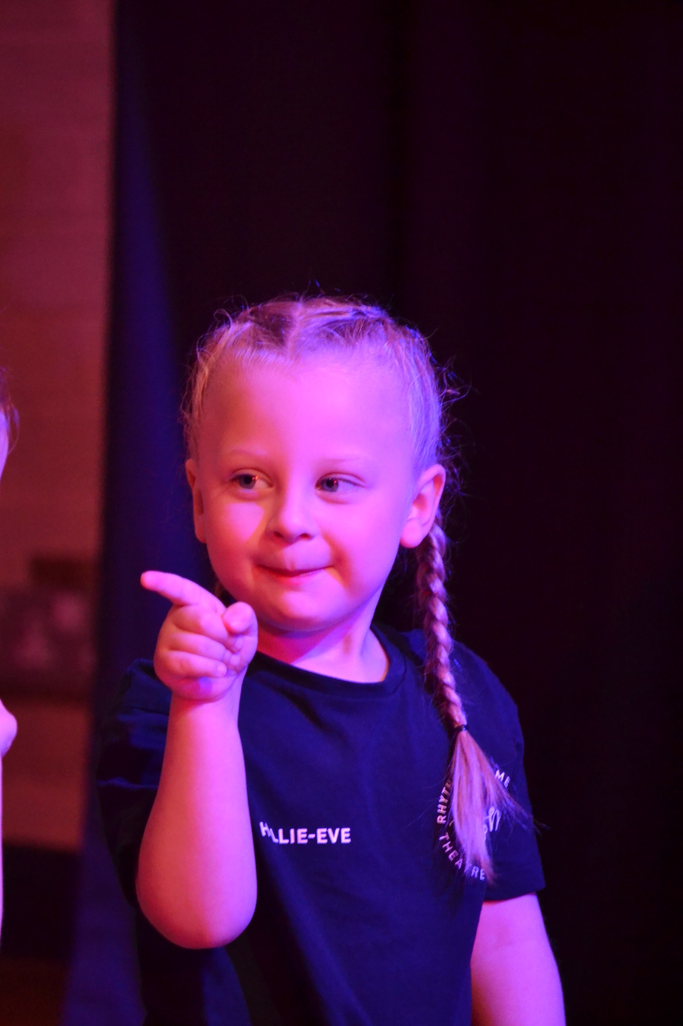 A young performer points during a routine against a dark backdrop.