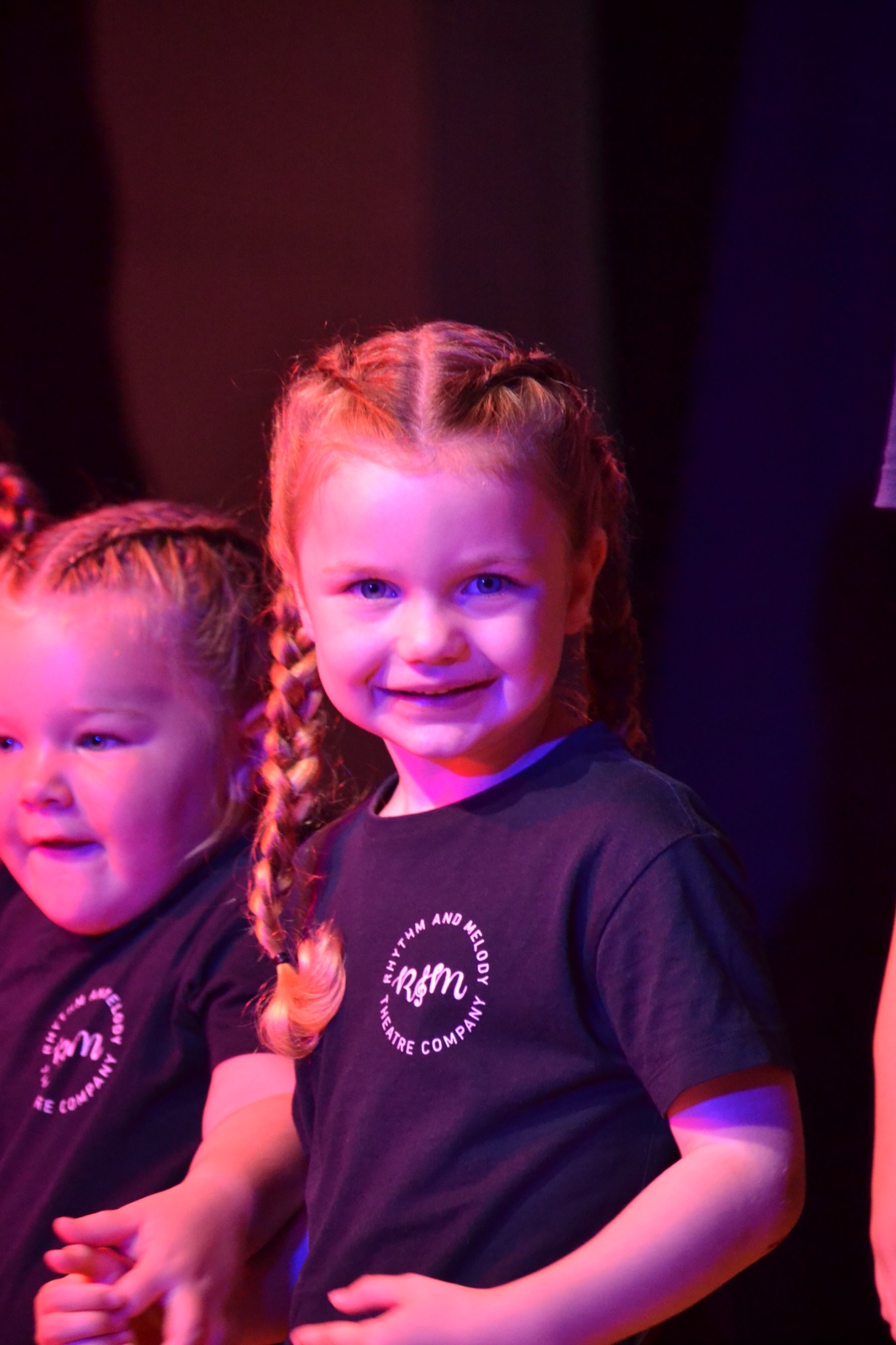 Young performers smile together in their performance T-shirts.
