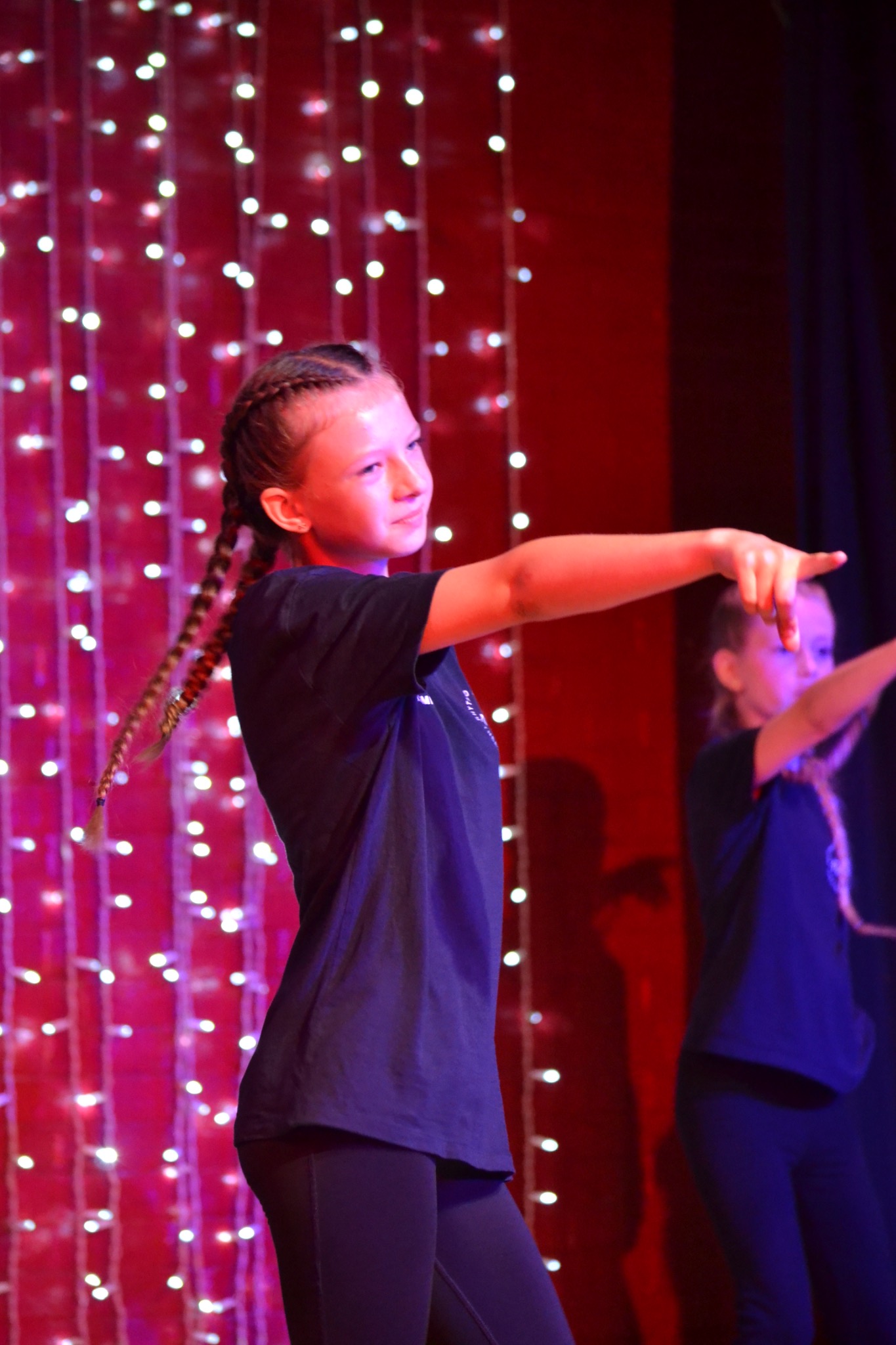 A performer reaches out during a group dance on stage.